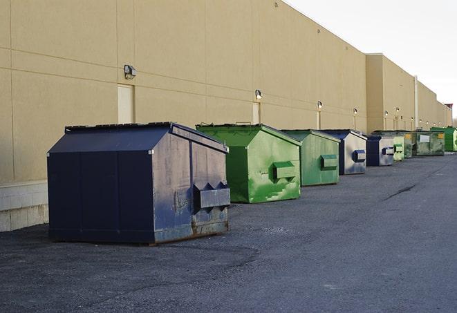 a construction worker unloading debris into a blue dumpster in Bloomfield KY